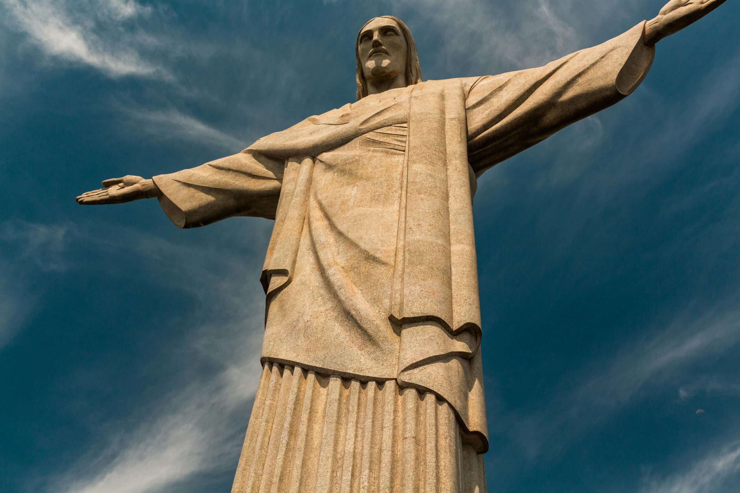 Low angle view of Christ the Redeemer statue against a blue sky in Rio de Janeiro, Brazil.